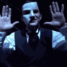 a man is wearing a white mask and a black vest