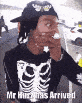 a man wearing a skeleton shirt and a hat says mr huzz has arrived