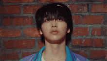 a close up of a person leaning against a brick wall looking up .