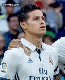 a soccer player wearing a fly emirates shirt stands in front of a crowd .