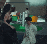 a woman in a black dress stands next to a man in a white suit