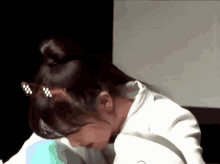 a woman wearing glasses and a bun is laying down