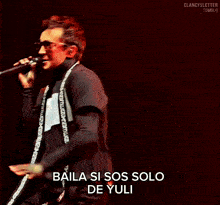 a man singing into a microphone with the words baila si sos solo de yuli below him