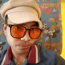 a man wearing a hat and sunglasses stands in front of a mickey mouse curtain that says disney on it