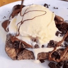 a close up of a dessert with ice cream and chocolate sauce on a white plate