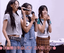 three girls singing into microphones in a room with korean writing on the bottom
