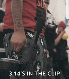 a man in a red shirt is holding a gun in his hand and says `` 3 14 's in the clip '' .