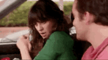 a man and a woman are sitting in a car and the woman is talking on the phone .