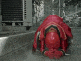 a person in a red superhero costume is kneeling down