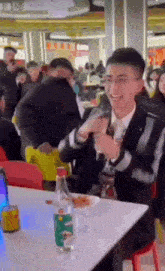 a man in a suit is sitting at a table with a bottle of water on it .