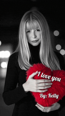 a woman holding a red heart with the words i love you by kelly