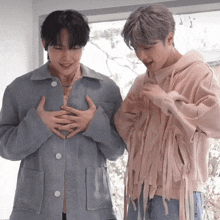 two young men are standing next to each other and one is wearing a pink hoodie