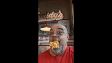 a man in a red shirt is eating french fries in front of a sign that says freddy 's