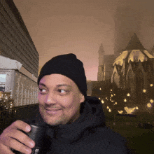 a man wearing a black beanie is holding a cup with the letter e on it