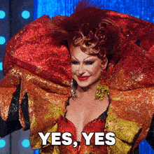 a drag queen is wearing a red and gold costume with the words yes yes written below her