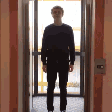 a man in a black sweater is standing in an elevator doorway
