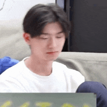 a young man is sitting on a couch with his eyes closed and looking at something .