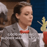 a woman in a suit and tie is sitting at a table with a bloody mary in front of her .
