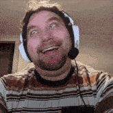 a man wearing headphones and a microphone is smiling and making a funny face