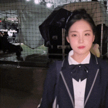 a woman wearing a suit and bow tie is standing in front of a net