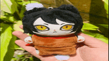 a person is holding a stuffed animal with yellow eyes in their hand