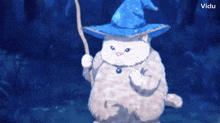 a white cat wearing a blue wizard hat is holding a stick .