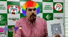 a man wearing a clown wig stands in front of a santa cruz poster