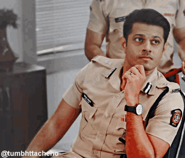 a man in a police uniform is sitting with his hand on his chin