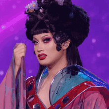 a woman in a costume with a purple background is holding something