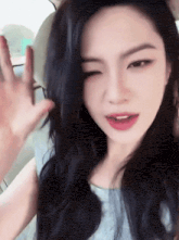 a woman with long black hair is sitting in a car and waving