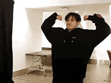 a man in a black sweatshirt with the word stay on it flexes his muscles