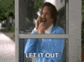 a man in a blue jacket is talking on a cell phone in a phone booth .