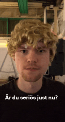 a man wearing a wig and a black shirt with the words ar du serios just nu on the bottom