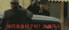 a man in a hat holds a gun in front of a car with chinese writing