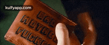 a person is holding a brown leather wallet with the words `` god loves you '' on it .