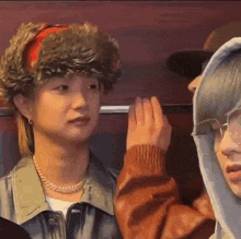 a man wearing a fur hat is whispering into another man 's ear while sitting next to another man .