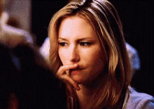 a close up of a woman 's face with her finger to her mouth