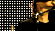 a person is singing into a microphone in front of a polka dot backdrop