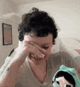 a woman is covering her face with her hand in front of a framed picture that says " loved sme2u "