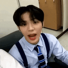 a man wearing suspenders and a tie is sitting on a couch