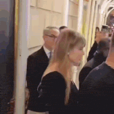 a woman in a black dress is walking down a hallway next to a man in a suit .
