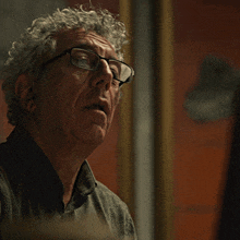 a man with curly hair wearing glasses looks at the camera