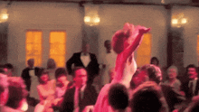 a woman in a pink dress is dancing in a crowd
