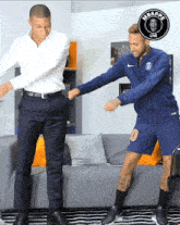 two men are dancing in front of a sign that says mbappe live on it