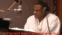 a man wearing headphones is sitting in front of a microphone with the words " but do not waste my time with talk " above him