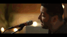 a man singing into a microphone with a candle in the background
