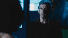 a man is standing in front of a woman in a dark room .