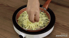a person is putting cheese on an omelet in a pan that says made in animatica
