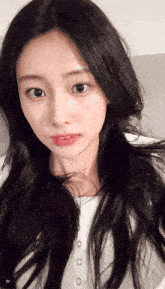 a woman with long black hair is wearing a white shirt with buttons on the front