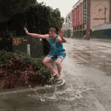 a man is riding a surfboard through a flooded street in front of a store called storage